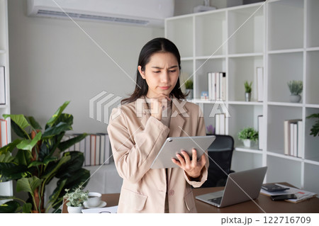 Unhappy Asian business woman shows stress over unsuccessful business while working in home office decorated with soothing green plants. 122716709