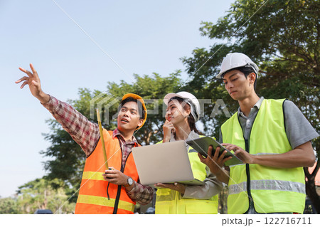 Construction team discussing project details engineer presenting ideas while reviewing plans on-site 122716711