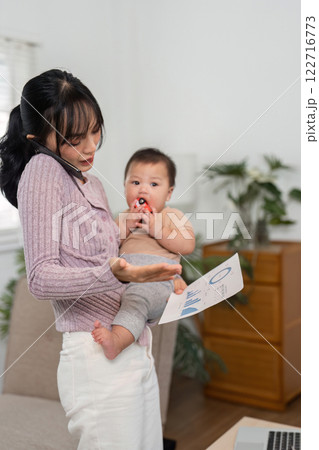 Working mother multitasking with baby on phone and documents at home. 122716773