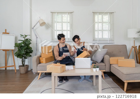 LGBT couple managing their online business together, packing orders at home LGBT couple managing their online business together, packing orders at home 122716918