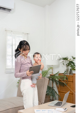 Multitasking mother using tablet while holding her baby, blending technology and parenting at home Multitasking mother using tablet while holding her baby, blending technology and parenting at home 122717077