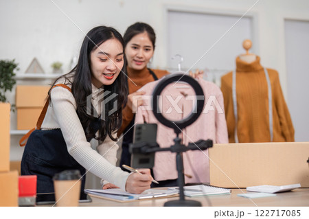 Couple selling clothes online, enthusiastically documenting their pink sweater and preparations in a chic home office Couple selling clothes online, enthusiastically documenting their pink sweater and preparations in a chic home office 122717085