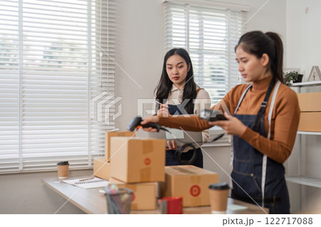 Focused online sellers working together to process orders using barcode scanners in their bustling boutique Focused online sellers working together to process orders using barcode scanners in their bustling boutique 122717088
