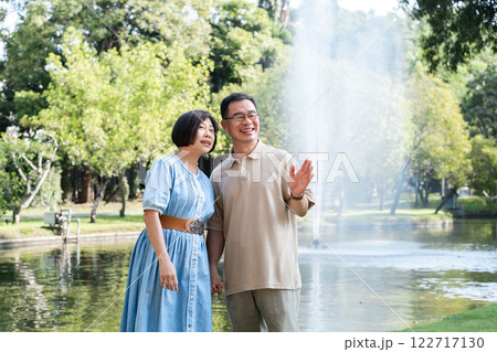A retired couple walks outside together in the park on a relaxing vacation. A retired couple walks outside together in the park on a relaxing vacation. 122717130