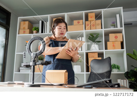 Businesswoman preparing plans and checking supplies in a modern office with packaging supplies Businesswoman preparing plans and checking supplies in a modern office with packaging supplies 122717172