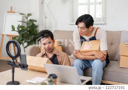 Entrepreneurs reviewing product details on laptop in their home office with packages Entrepreneurs reviewing product details on laptop in their home office with packages 122717191