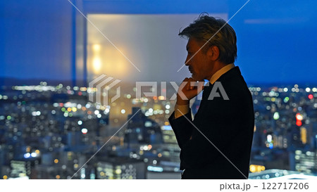 都市の夜景を背景に考えるビジネスパーソン 都市の夜景を背景に考えるビジネスパーソン 122717206