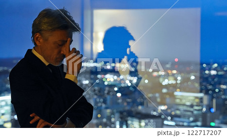 都市の夜景を背景に考えるビジネスパーソン 122717207