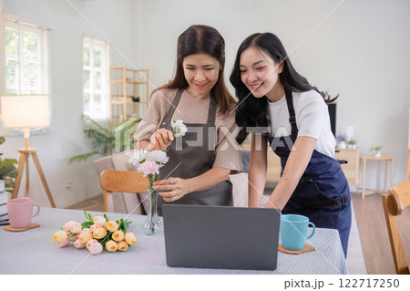 Middle-aged daughter happily arranges flowers with her mother at home Free time activities that are done together as a family 122717250