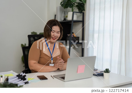 Young Businesswoman Conducts Online Meeting Presenting Financial Graphs in Modern Office Setting Young Businesswoman Conducts Online Meeting Presenting Financial Graphs in Modern Office Setting 122717414
