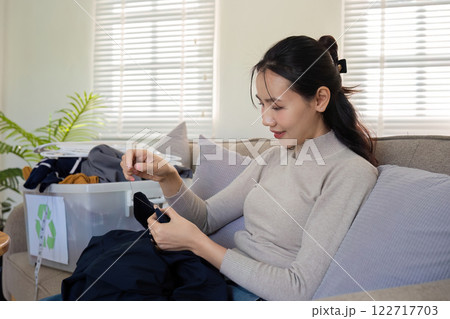 beautiful young woman sewing Repair damaged clothes so that it can be reused. In order to reduce the creation of waste and reduce environmental pollution. 122717703