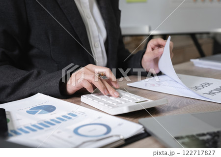 Asian female accountant working on calculations on table in office Asian female accountant working on calculations on table in office 122717827