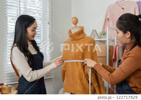 Women tailoring experts measuring a knitted sweater on a mannequin, emphasizing collaboration and precision in fashion design Women tailoring experts measuring a knitted sweater on a mannequin, emphasizing collaboration and precision in fashion design 122717829