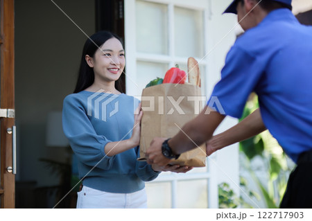 delivery man Deliver a paper bag package to the beautiful woman at the front of the house according to the order. delivery man Deliver a paper bag package to the beautiful woman at the front of the house according to the order. 122717903