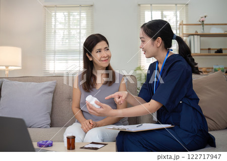A caregiver is giving advice on health care and medication to an elderly woman at home. 122717947