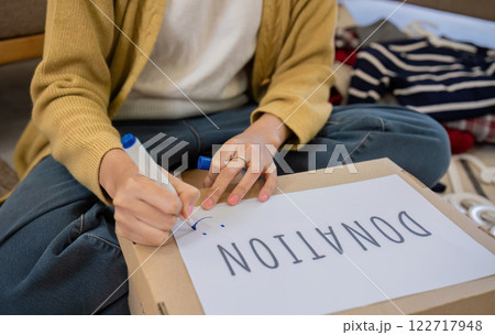 A beautiful Asian woman uses a magic marker to write on a box of clothes that will be donated to show moral support. 122717948