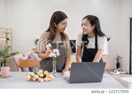 Middle-aged daughter happily arranges flowers with her mother at home Free time activities that are done together as a family Middle-aged daughter happily arranges flowers with her mother at home Free time activities that are done together as a family 122717950