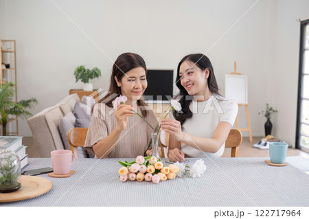 Middle-aged daughter happily arranges flowers with her mother at home Free time activities that are done together as a family Middle-aged daughter happily arranges flowers with her mother at home Free time activities that are done together as a family 122717964