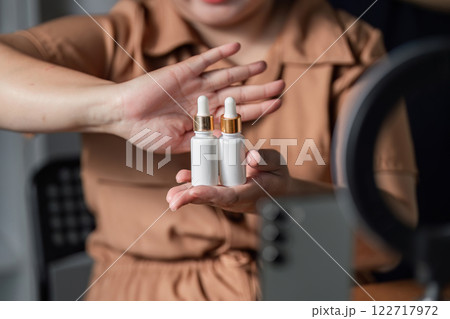 Skincare influencer showcasing premium facial serums during a live stream in her home studio Skincare influencer showcasing premium facial serums during a live stream in her home studio 122717972