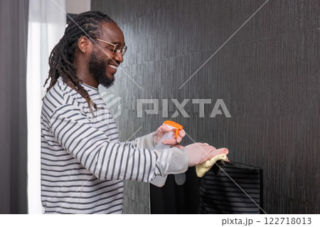 African man in casual clothes Clean dust or dirt in the room. Stand holding cleaning supplies and smile for the camera. 122718013