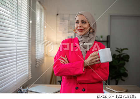 Confident Muslim businesswoman standing in front of desk in office 122718108