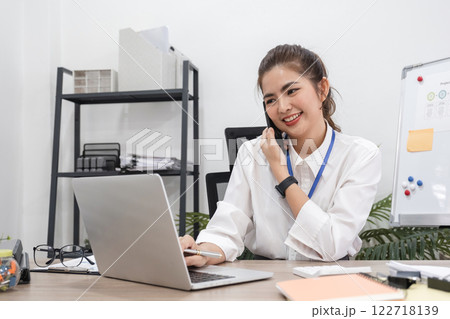 Beautiful business woman working with laptop, recording data and discussing work over the phone in modern office Beautiful business woman working with laptop, recording data and discussing work over the phone in modern office 122718139