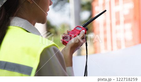 Close-up of a construction supervisor using a walkie-talkie for communication at a project site Close-up of a construction supervisor using a walkie-talkie for communication at a project site 122718259