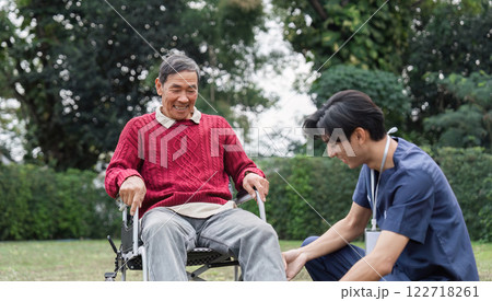 Senior man enjoying laughter with healthcare professional in a serene garden setting Senior man enjoying laughter with healthcare professional in a serene garden setting 122718261