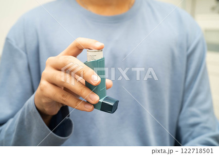 Asthma and chronic obstructive pulmonary disease COPD, Asian young man using metered dose inhaler MDI. 122718501
