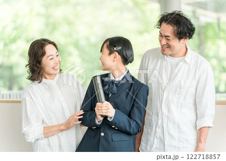 卒業証書を持つ中学生の女の子と両親 122718857