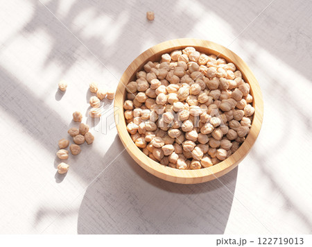 Dried chickpea in wooden bowl on white board background with sunshine. copy space,top view. Dried chickpea in wooden bowl on white board background with sunshine. copy space,top view. 122719013