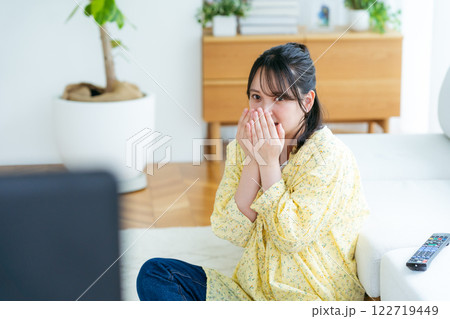 リビングでテレビを見ながら怖がる若い女性 リビングでテレビを見ながら怖がる若い女性 122719449