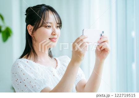 部屋でスマホを操作する若い女性 122719515