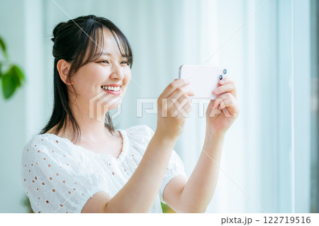 部屋でスマホを操作する若い女性 部屋でスマホを操作する若い女性 122719516
