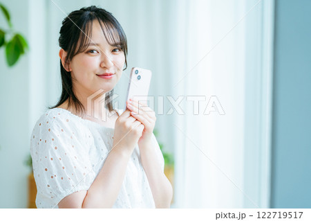 部屋でスマホを操作する若い女性 部屋でスマホを操作する若い女性 122719517