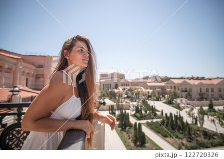 Woman Balcony View University Campus - Young woman looks out over a university campus from a balcony. Woman Balcony View University Campus - Young woman looks out over a university campus from a balcony. 122720326