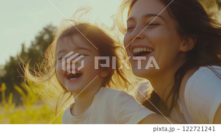 Happy mother and daughter laughing together in a field at sunset 122721241