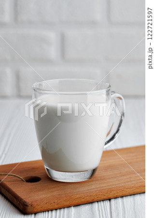milk in glass cup on table with white brick wall on the background 122721597