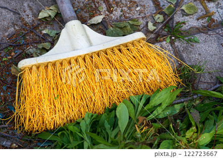 Cleaning the yard.Yellow plastic mop sweeping trash Cleaning the yard.Yellow plastic mop sweeping trash 122723667