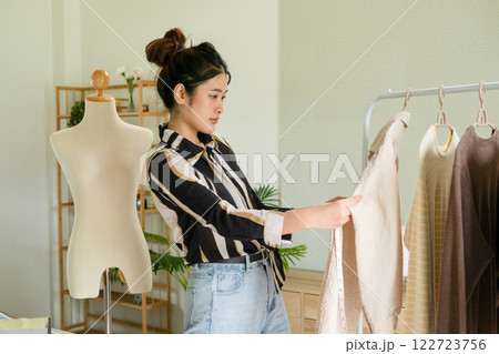 Young clothing designer taking measures of her clothes. 122723756