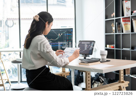 Young woman examines stock graphs and files at office desk Young woman examines stock graphs and files at office desk 122723826