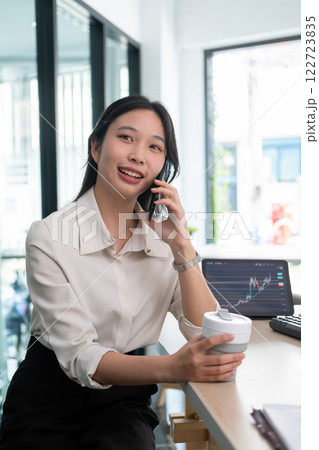 Woman examines stock graphs and talks on phone 122723835