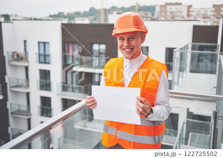Young architect wearing a protective helmet standing on the mountains building outdoor background Young architect wearing a protective helmet standing on the mountains building outdoor background 122725502