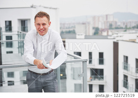 Smiling young architect or engineering builder in hard hat with tablet over group of builders at construction site, architect watching some a construction, business, building, industry, people concept 122725519