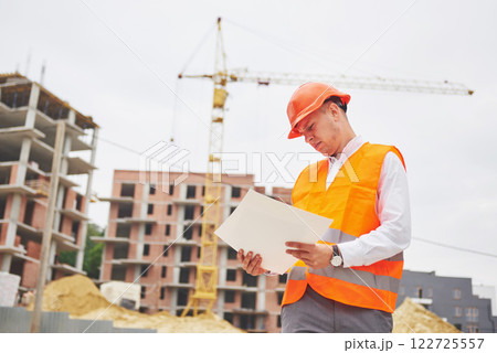 architecture and home renovation concept - man in helmet and gloves with blueprint in factory architecture and home renovation concept - man in helmet and gloves with blueprint in factory 122725557