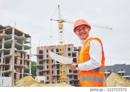 architecture and home renovation concept - man in helmet and gloves with blueprint in factory architecture and home renovation concept - man in helmet and gloves with blueprint in factory 122725572