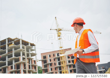 architecture and home renovation concept - man in helmet and gloves with blueprint in factory 122725580