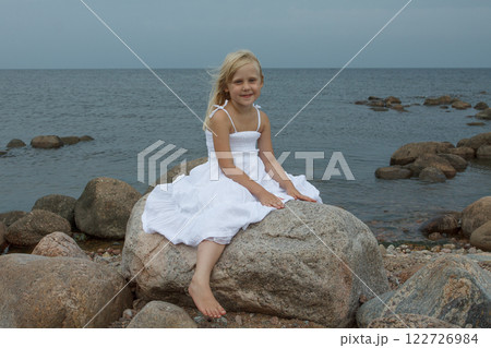 Portrait of beautiful cute girl sitting by the sea Portrait of beautiful cute girl sitting by the sea 122726984