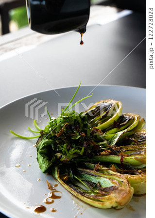 Bok choy is dressed with herbs and sauce, creating a colorful and tasty dish. 122728028