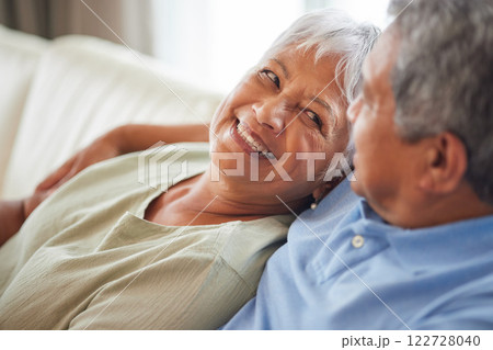 Happy, love and smile senior couple hugging relax and sitting on a couch at home. Man and woman lovers smiling and enjoying quality bonding together in the living room and having fun in the house 122728040